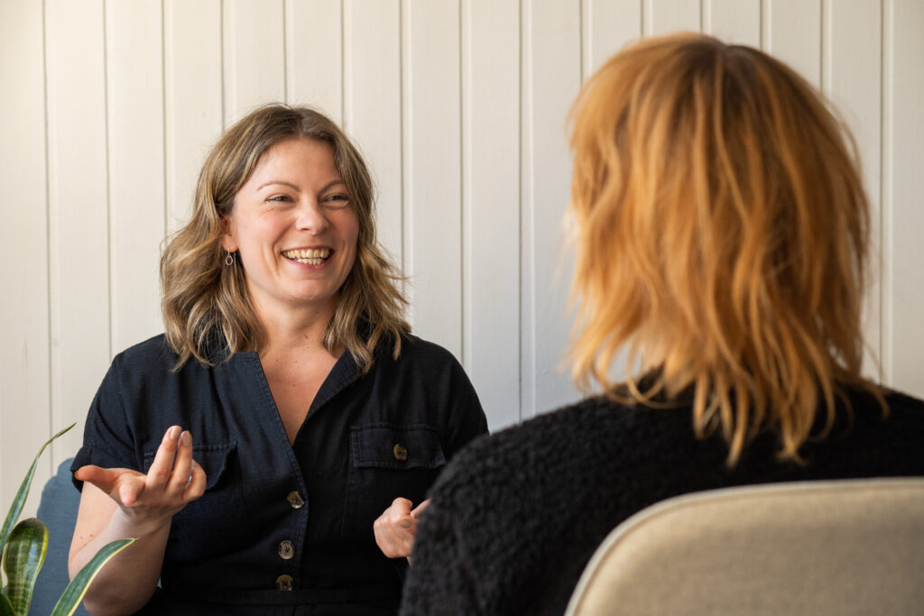Coaching as a Different Kind of Conversation ne-to-one coaching session: smiling coach engaged in conversation with a client during a professional consultation
