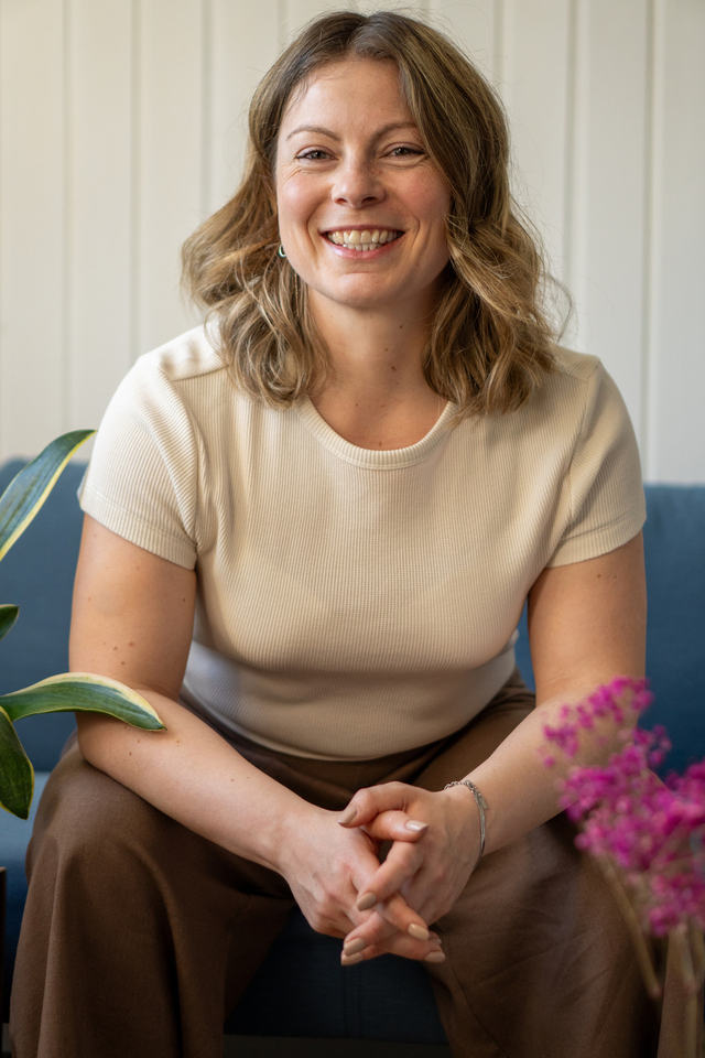 Sarah Pelham, coach and consultant, smiling and seated on a blue sofa